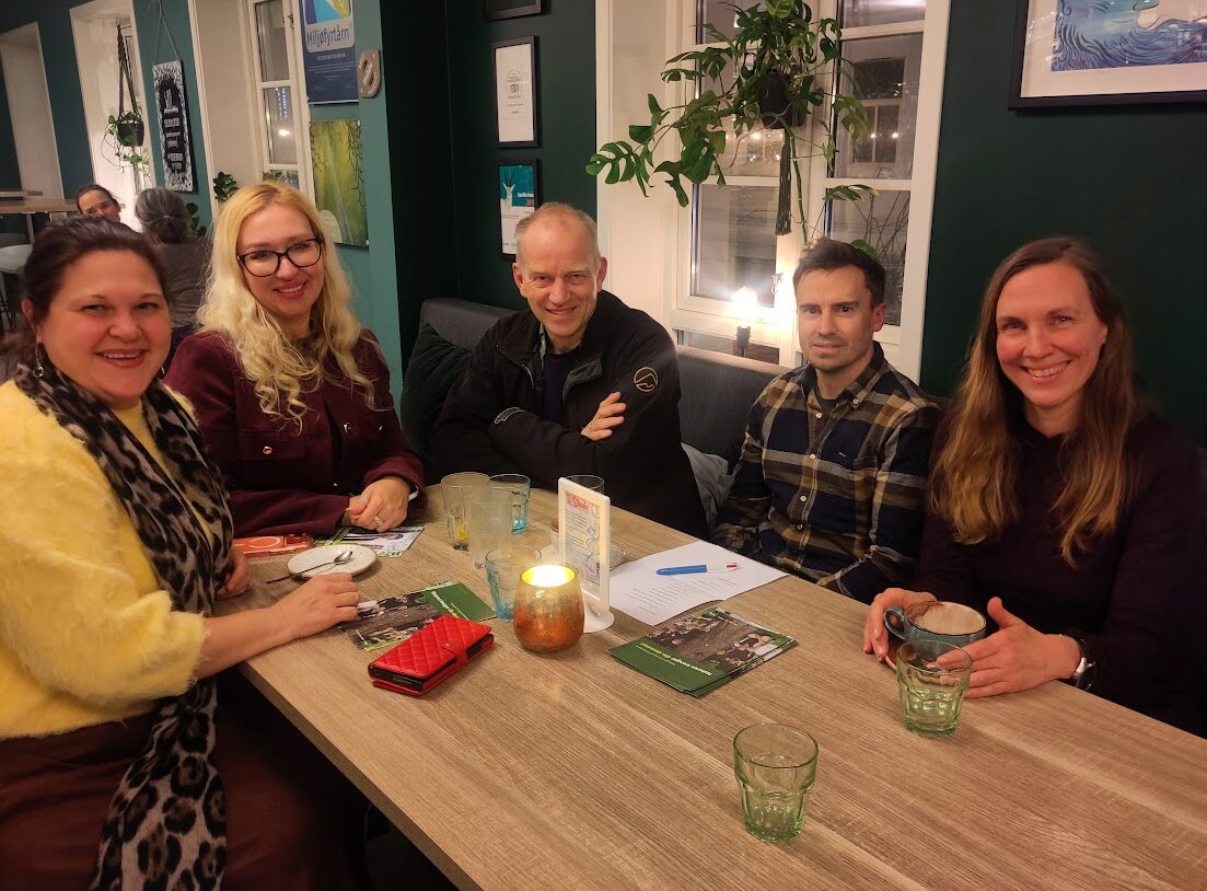 Fem mennesker rundt et kafebord med kopper på, 