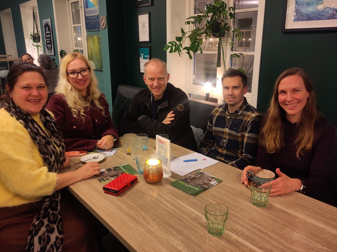 Fem mennesker rundt et kafebord med kopper på, 