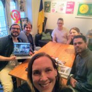 Fem studenter rundt et bord og en voksen gjest i forgrunnen (som har tatt bildet)